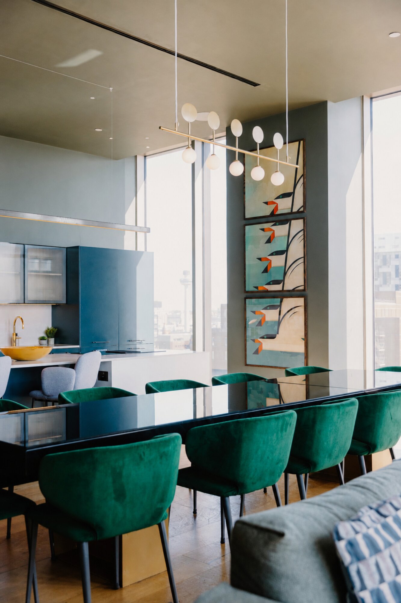 Private dining room with green velvet chairs, a long glass table and a kitchen of its own