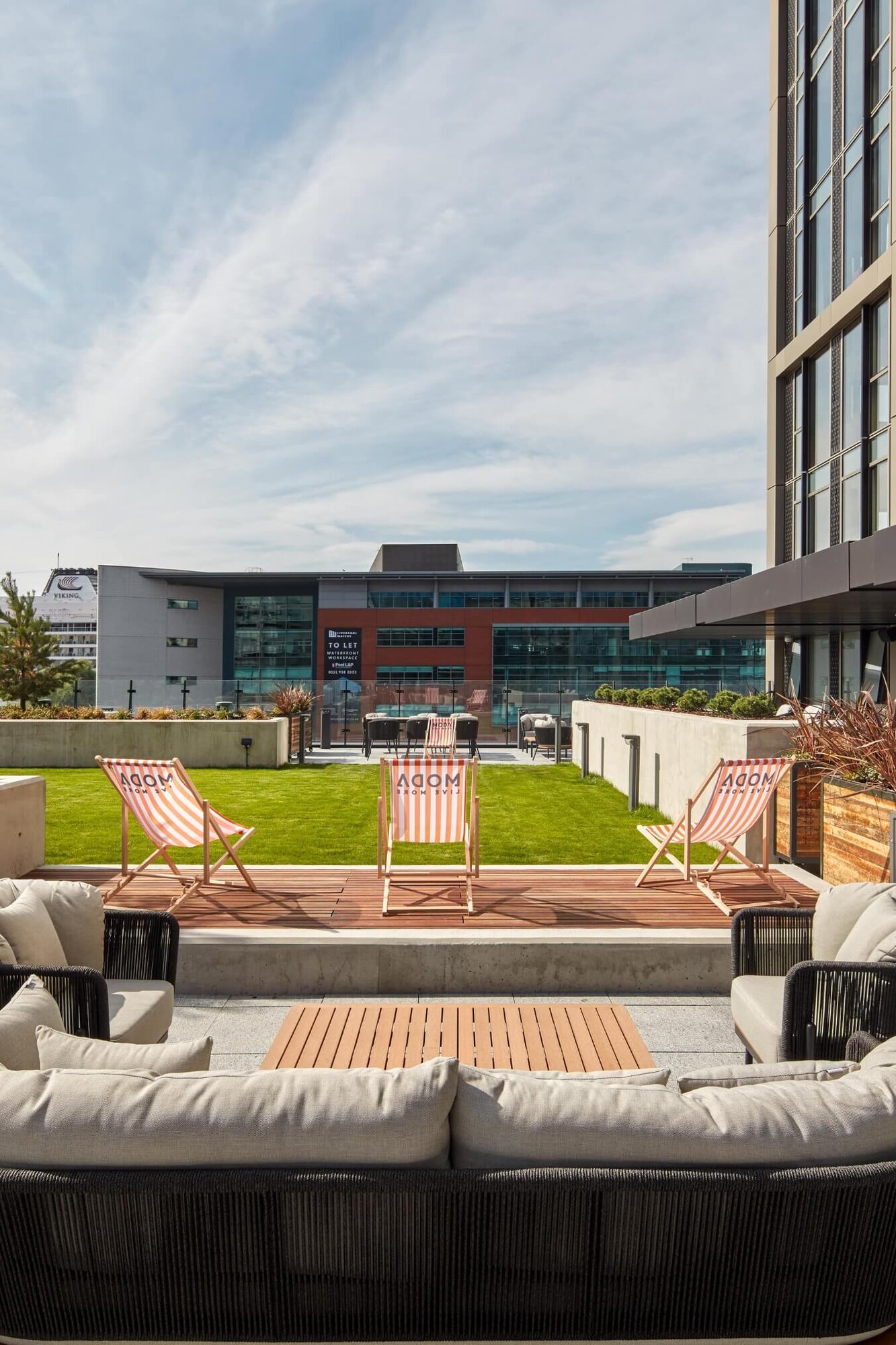 Roof terrace with a lawn, striped deckchairs and outdoor sofas