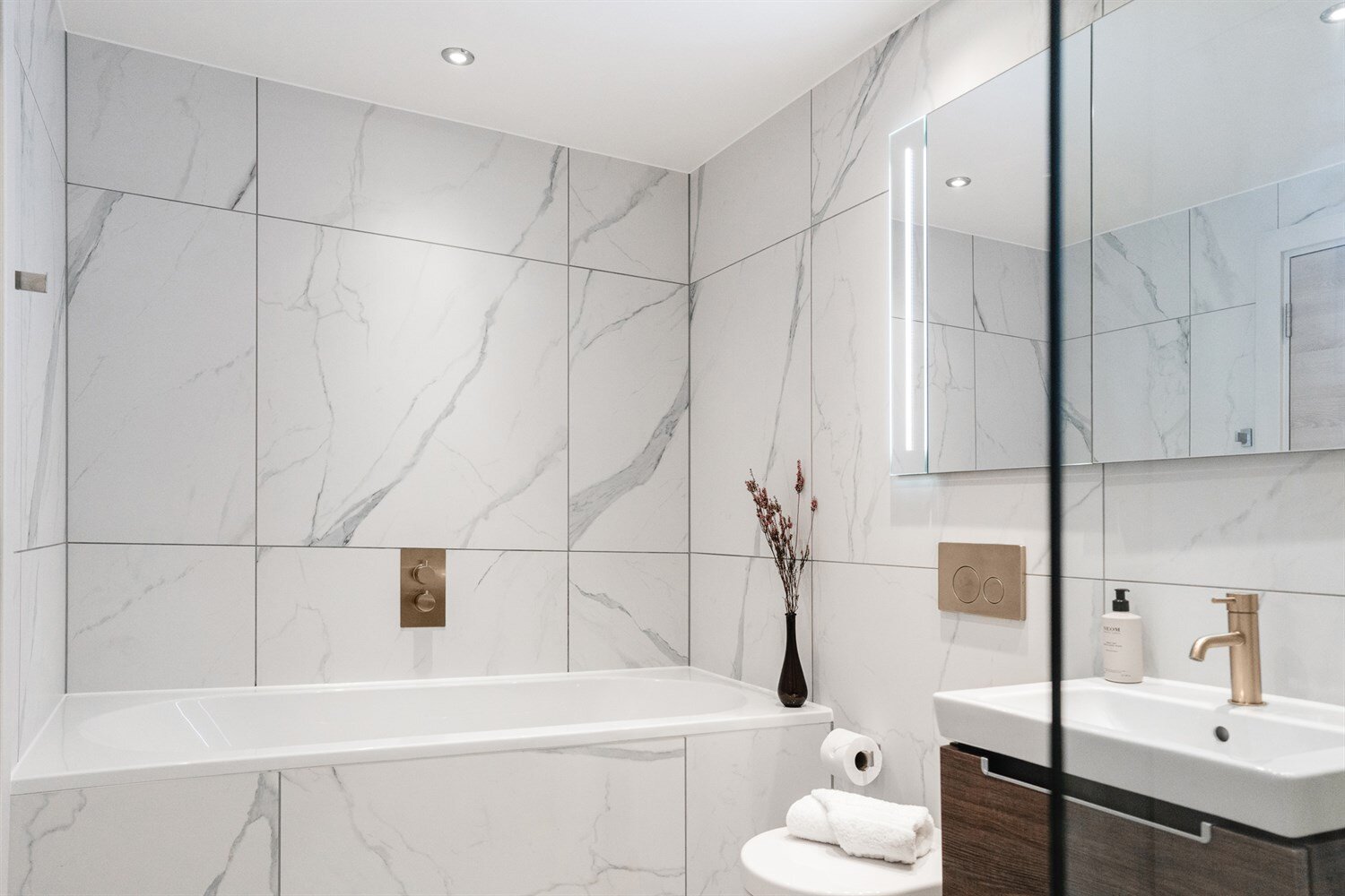 Bathroom with a bath, marble-effect tiles and brushed bronze taps