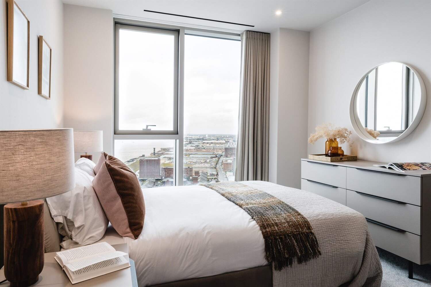 Bedroom with velvet cushions and a tall window over the docks and the River Mersey