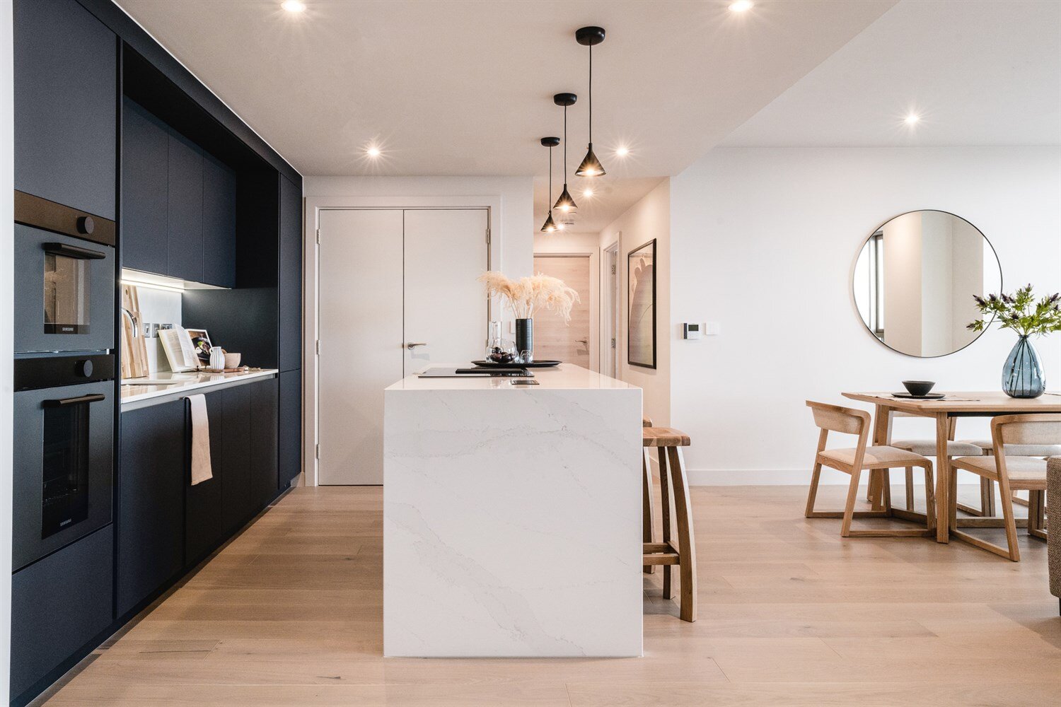 A marble waterfall island beside navy cabinetry, with the dining table beyond