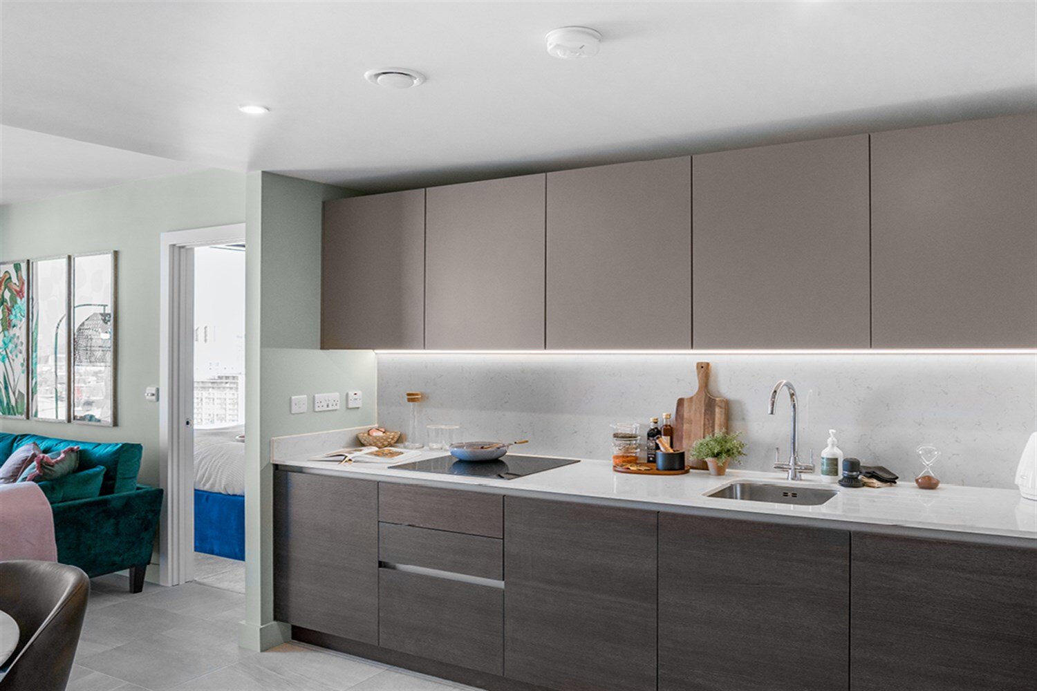 Kitchen with dark wood-grain units, a white splashback and a marble dining table, at The Mercian, Birmingham