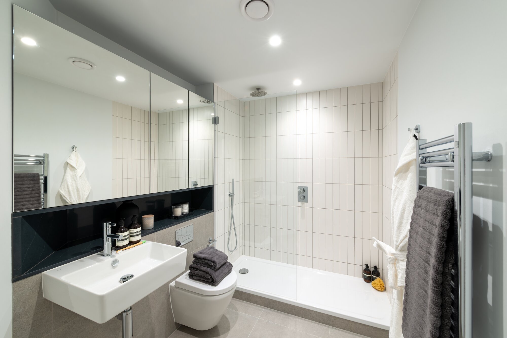 Shower room with white tiles, a wide mirrored cabinet and a heated towel rail, at The Octagon, Birmingham