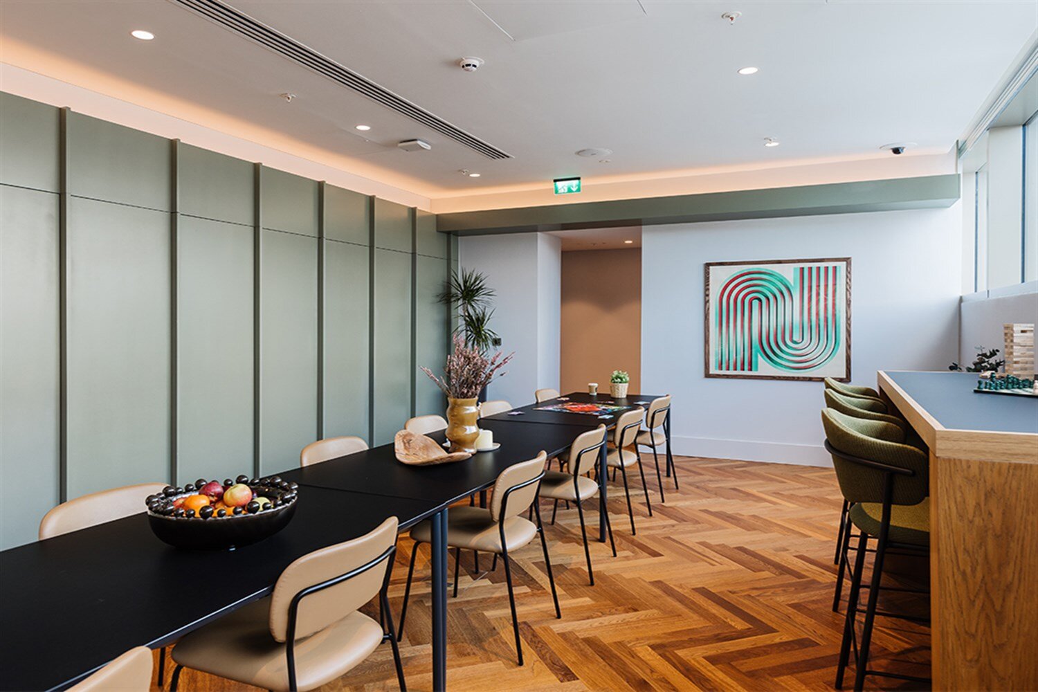 Co-working space with a long table, soft green walls and a coffee bar, at The Mercian, Birmingham