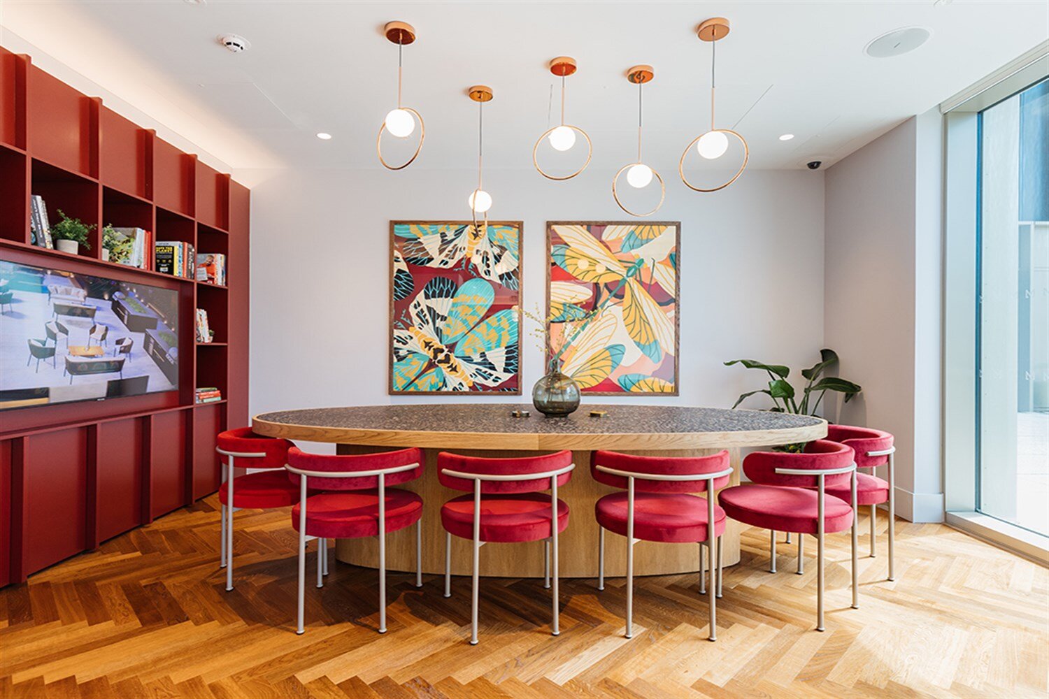 Private dining room with a round table, red chairs and bold botanical art, at The Mercian, Birmingham
