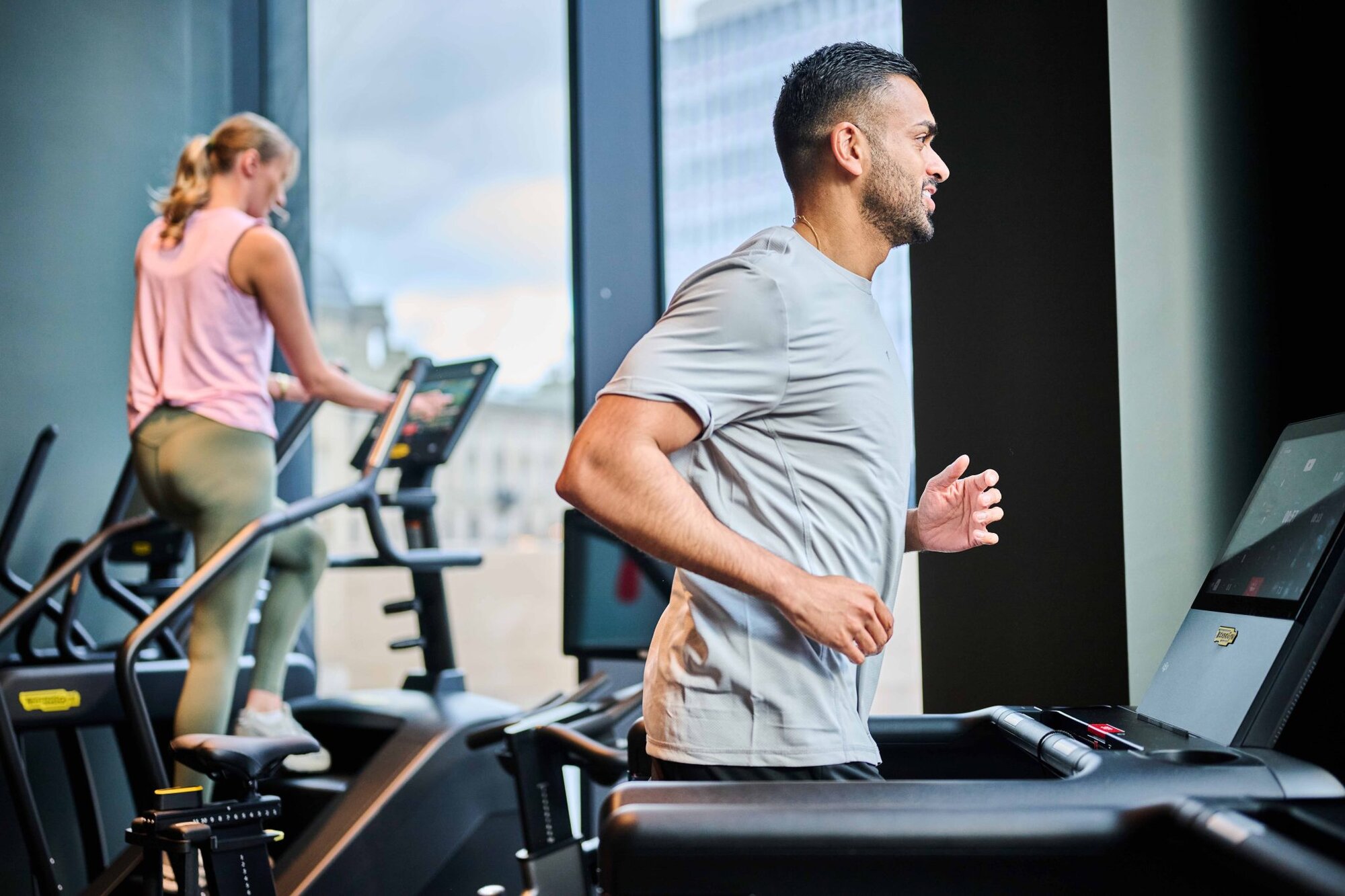 Residents running on treadmills and climbing a stair machine beside tall windows, at The Octagon, Birmingham