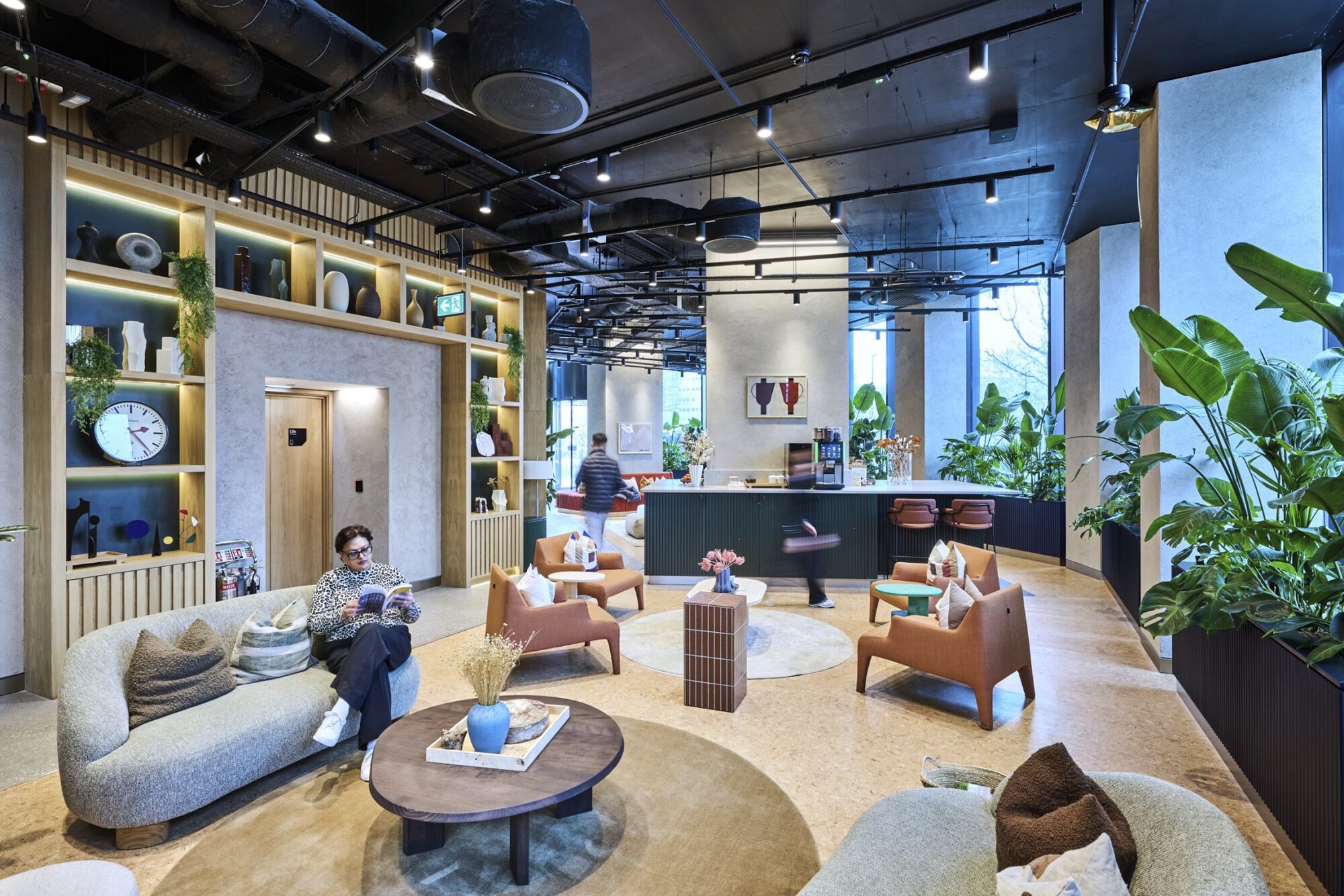 Residents' lounge with curved sofas, lit shelving and a long counter beneath an industrial ceiling, at The Octagon, Birmingham