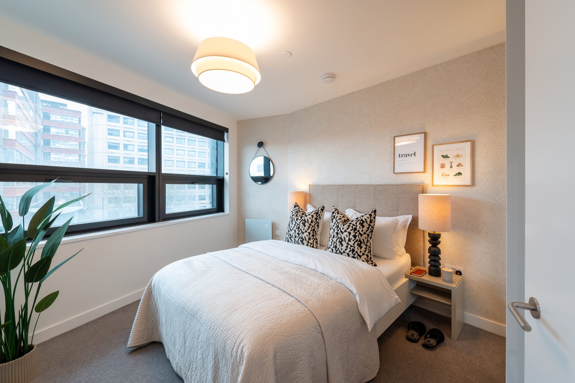 Bedroom with an upholstered headboard, patterned cushions and a wide window