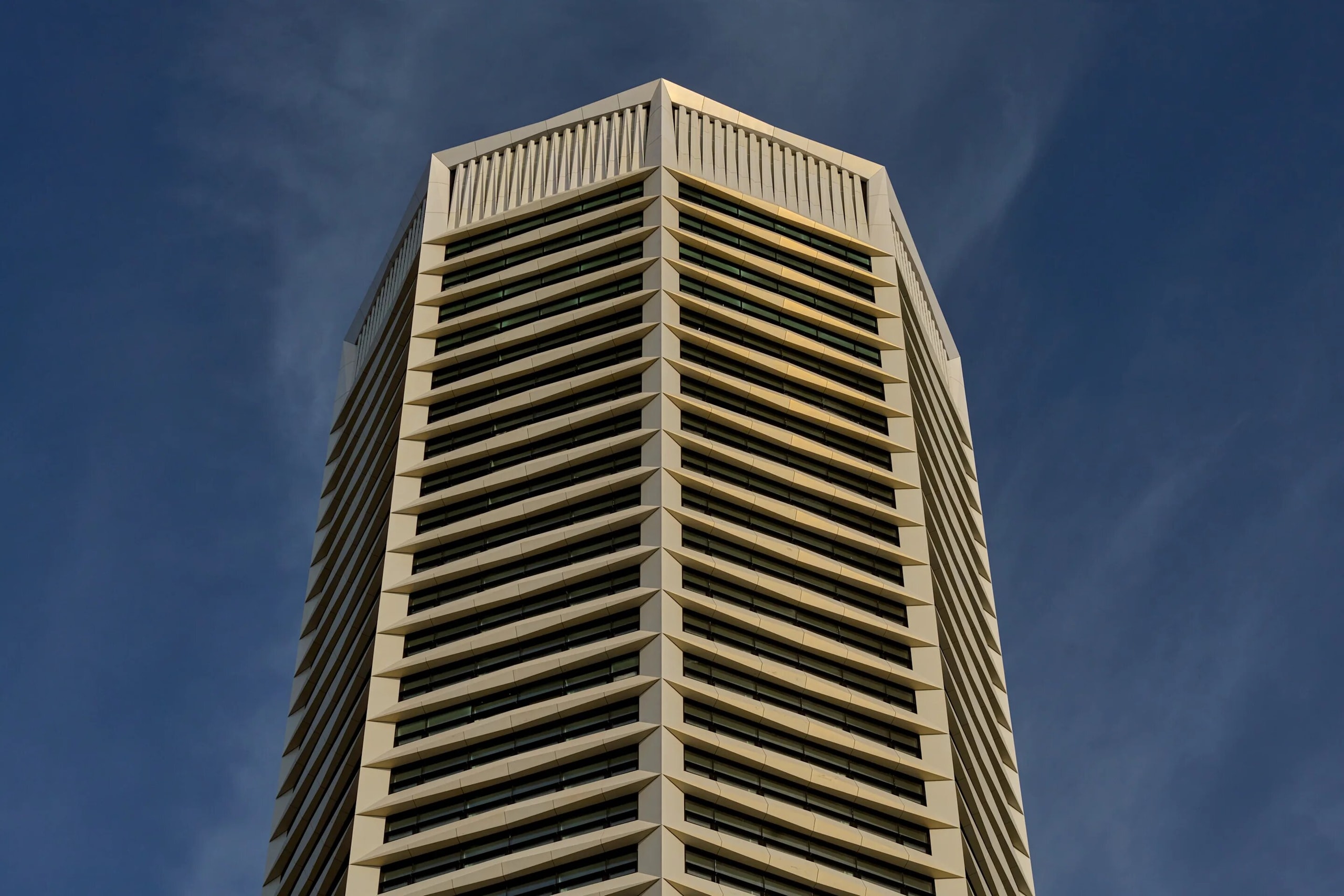 The crown of The Octagon, an eight-sided tower with pale ribbed facades, against a deep blue sky