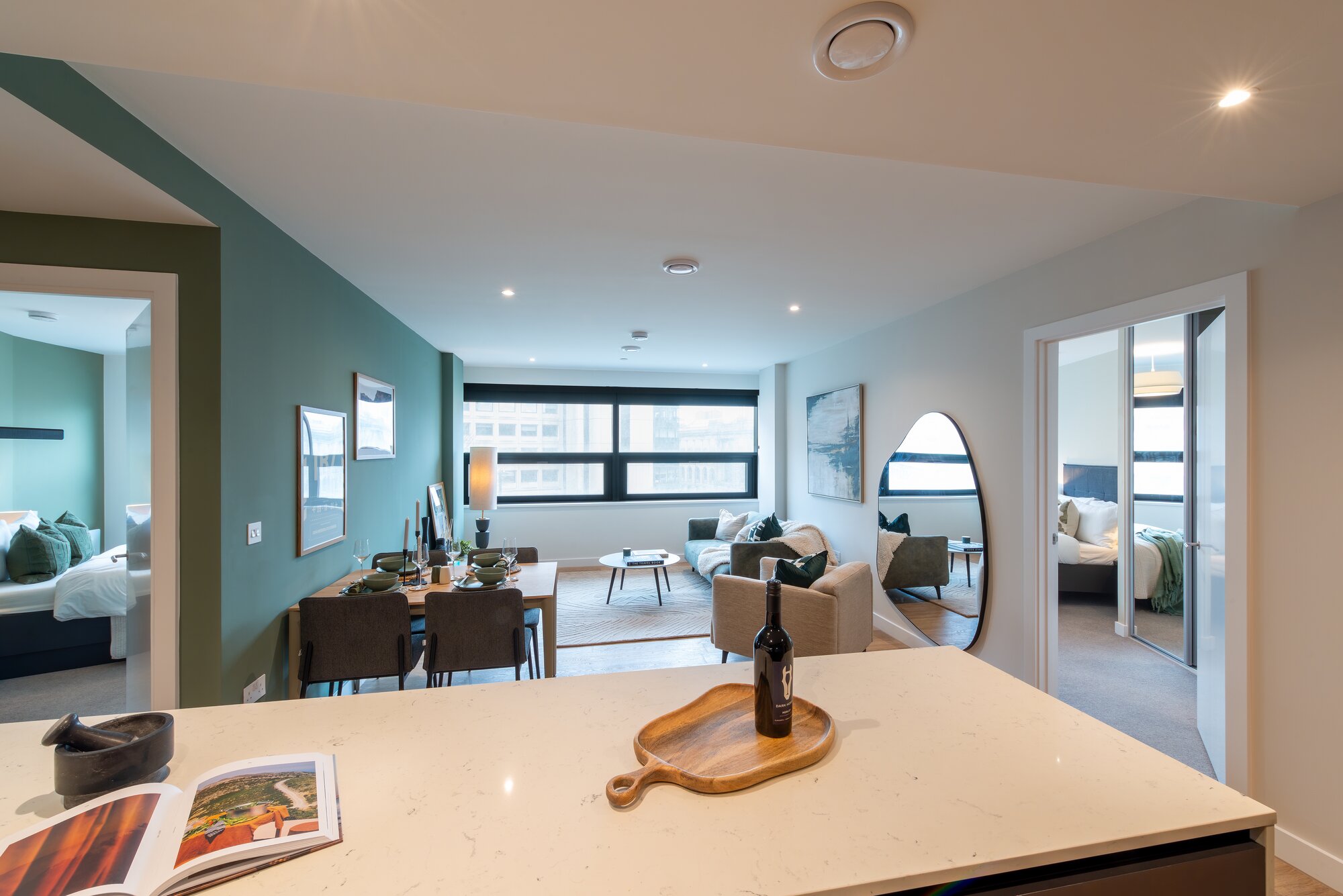 Kitchen island with a stone worktop looking through to the dining table and living room