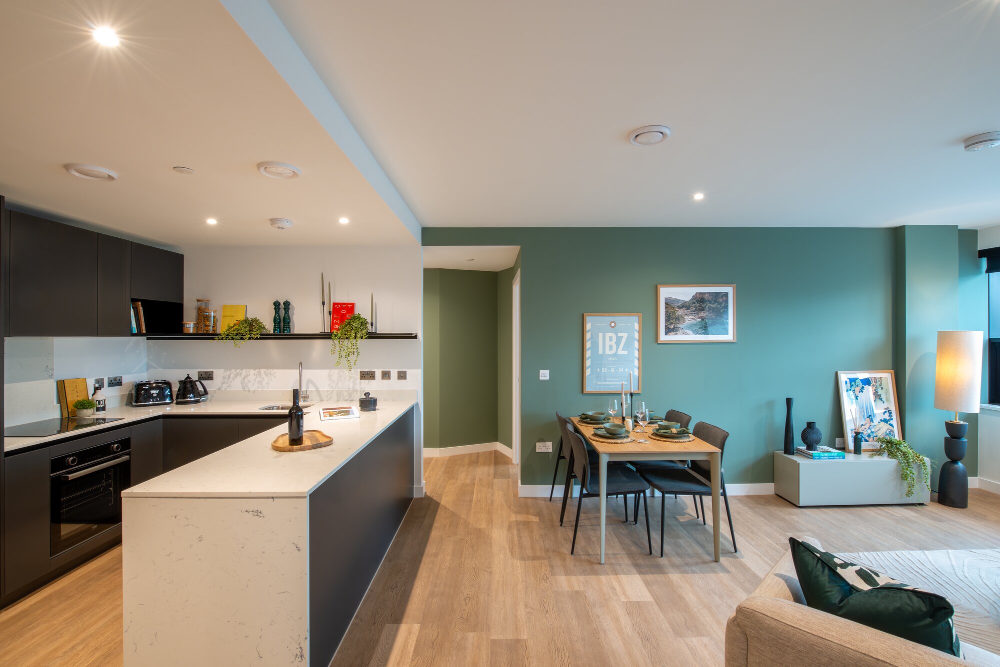 Open-plan kitchen and dining room with a teal wall, oak floors and long windows, at The Octagon, Birmingham