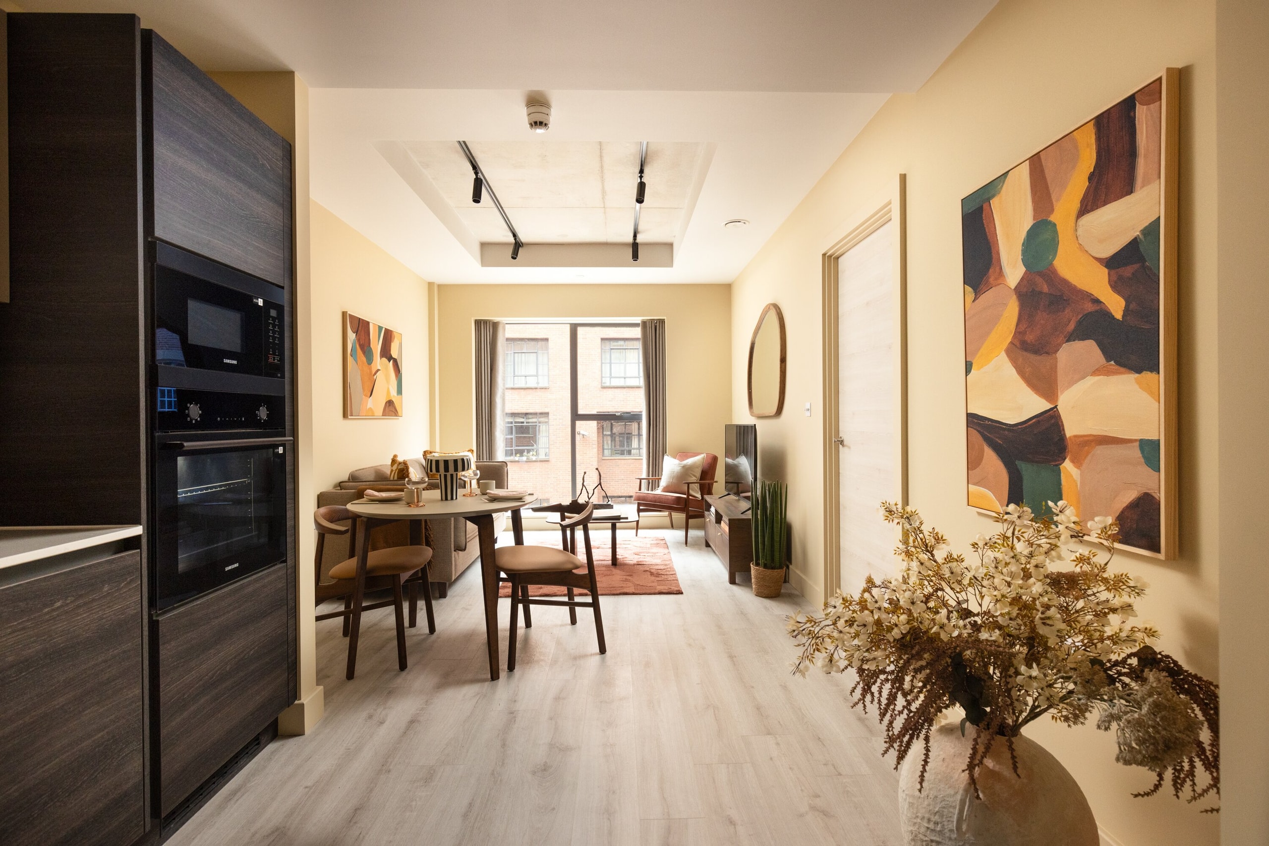 Open-plan kitchen, dining and living room with ochre walls and a large abstract painting