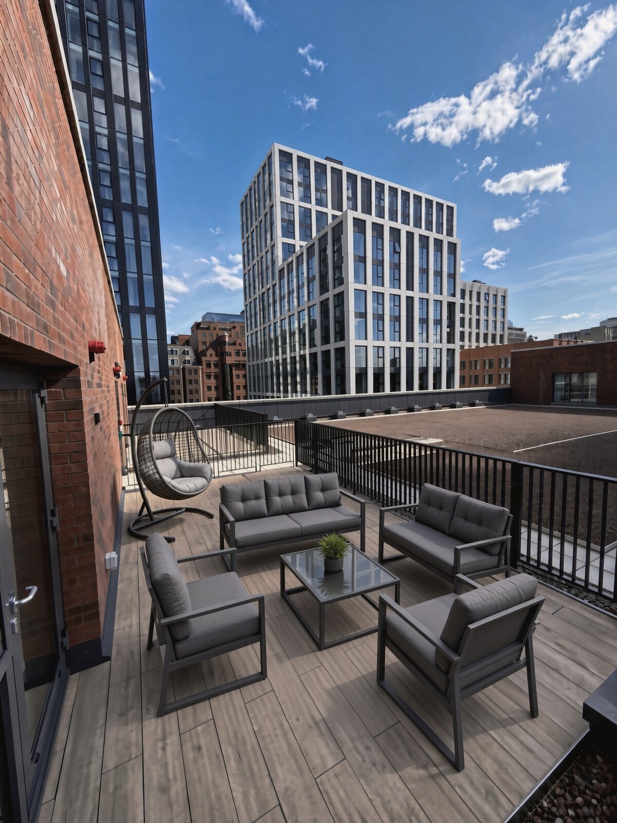 Roof terrace with outdoor sofas and a hanging chair, looking out over the city