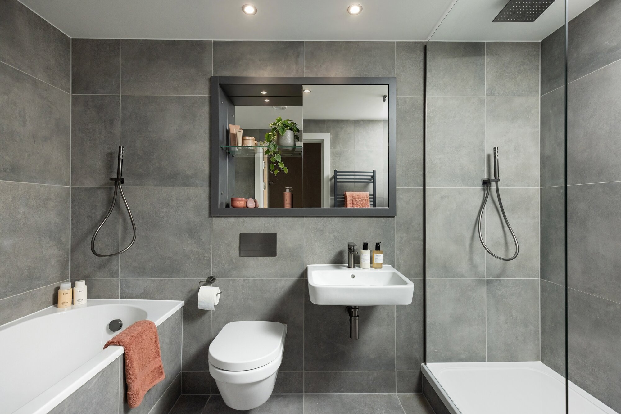 Bathroom with a bath, a separate shower and large grey tiles