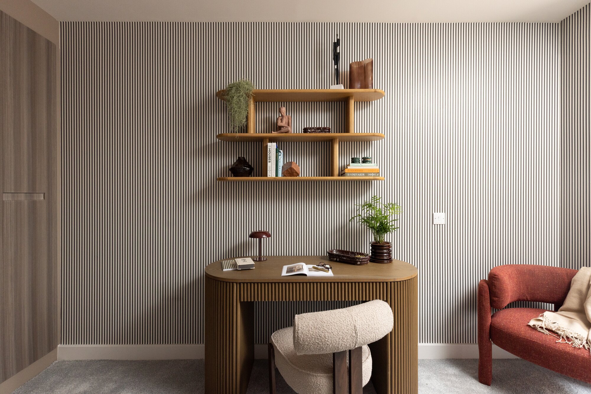 Fluted oak desk and a boucle chair beneath open shelves