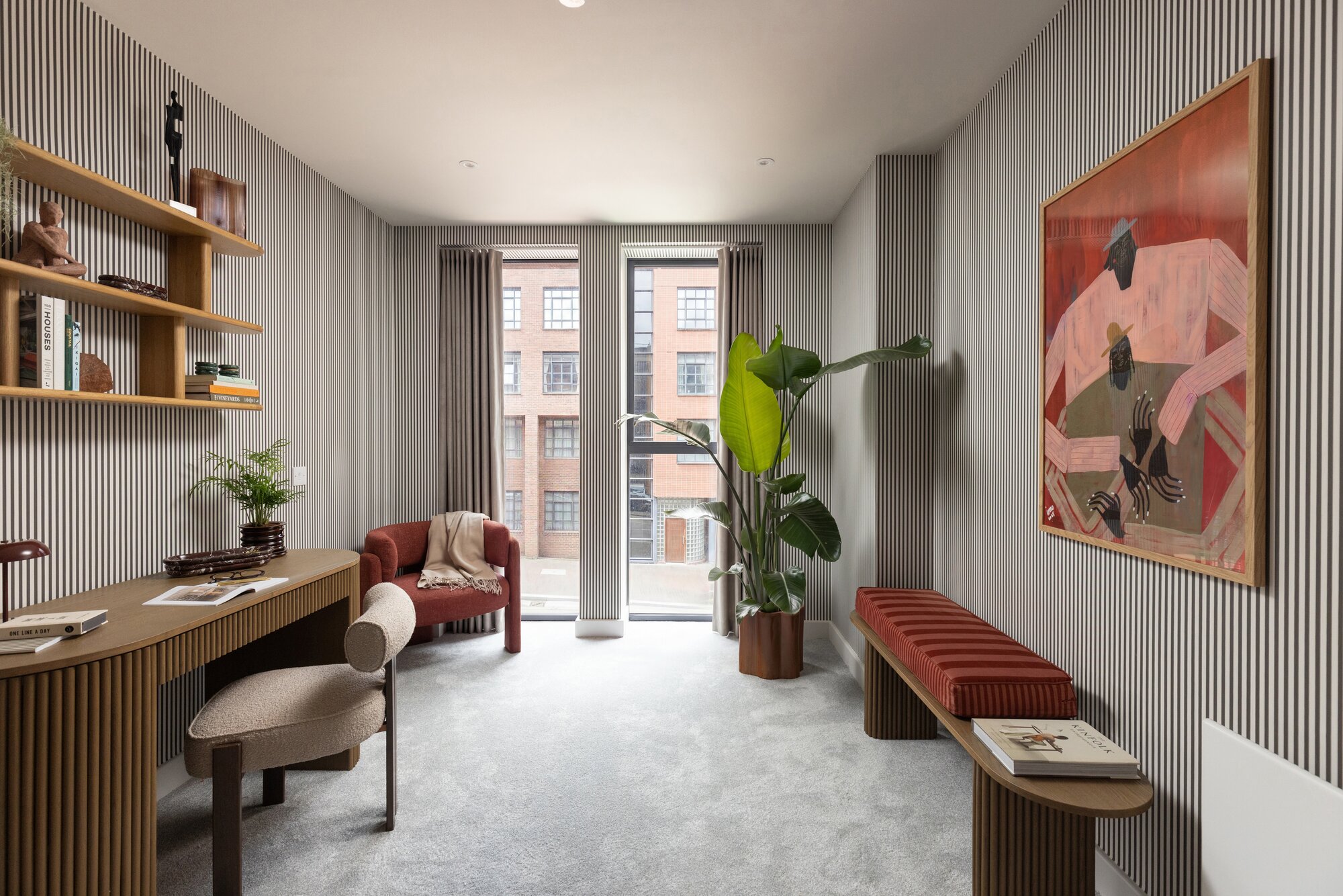 Study with a fluted desk, open shelving and tall windows