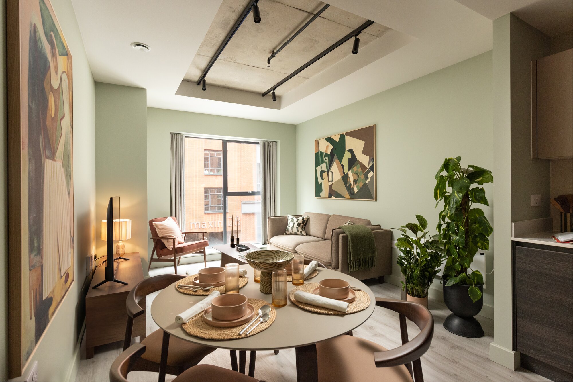 Round dining table laid for four, with plants and sage walls behind